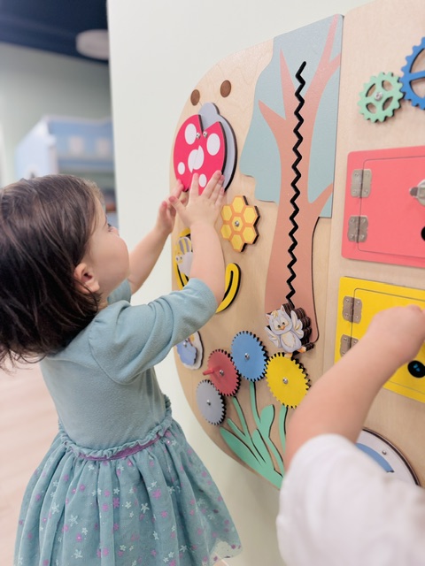 Child engaged with colorful interactive learning wall panel
