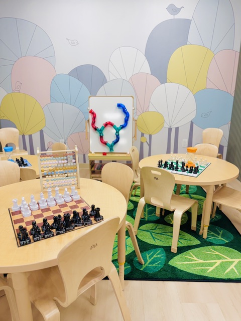 Chess and learning area with colorful tree mural wall and multiple chess boards set up