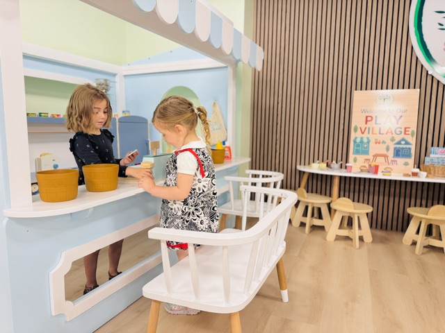Two children engaged in pretend play at the kitchen counter area