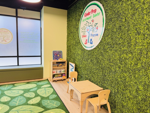 Learning area with beautiful green living wall, Kinder Prep signage, and wooden furniture